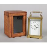 A brass carriage clock in fitted leather travel case. Clock including the handle, 14cm.