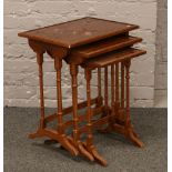 A nest of three yew wood occasional tables raised on turned legs.