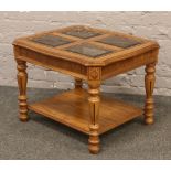 A light oak carved and turned two tier coffee table with four bevel edge glass panels.
