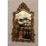 A large ornate gilt framed wall mirror, 143cm x 90cm.