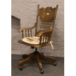 A modern carved oak office swivel arm chair raised on five spoke castered legs.