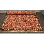 A red ground wool rug with geometric design, 235cm x 156cm.