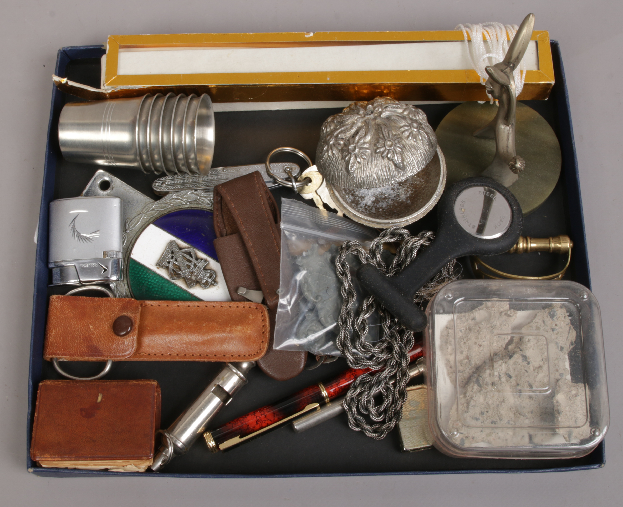 A tray of collectables including pocket knives, vintage lighter, Royal Hussars car badge and