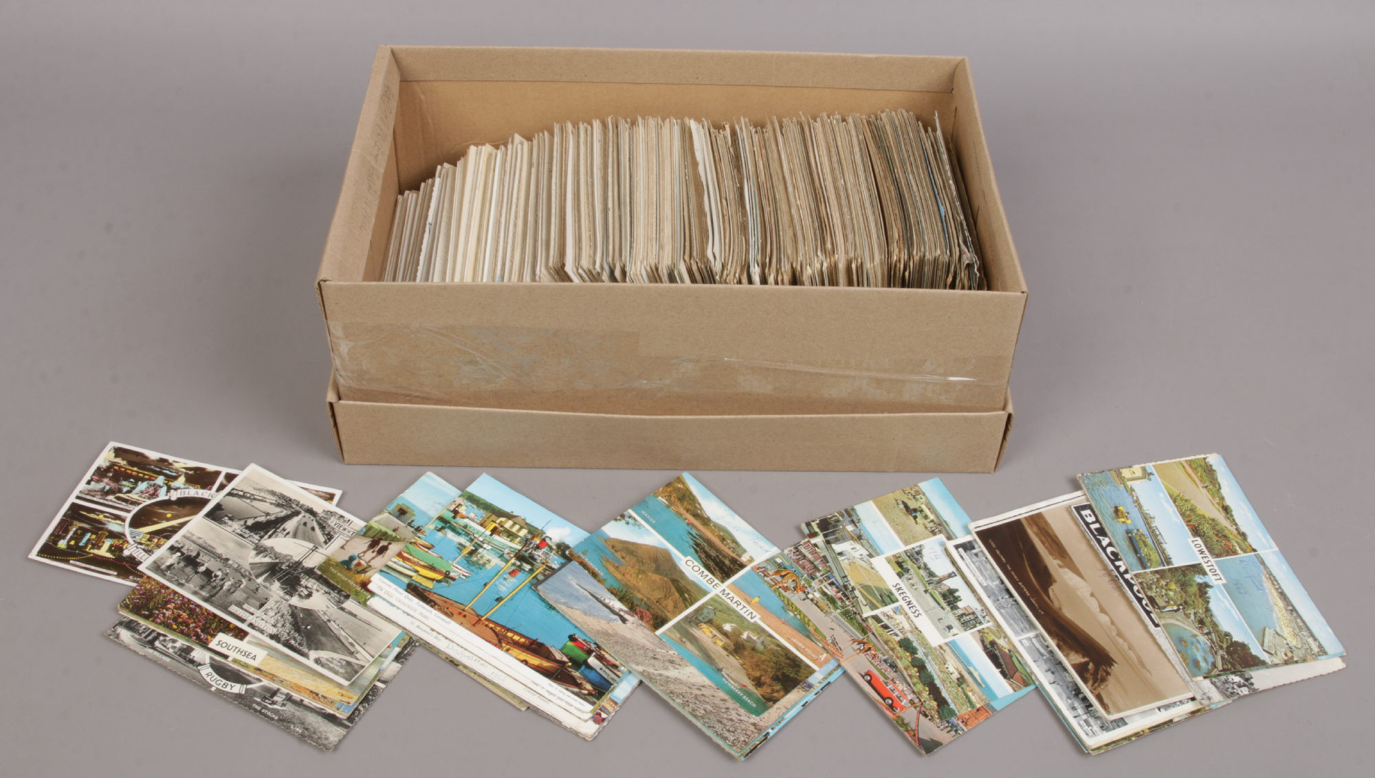 A shoe box of colour and monochrome postcards.