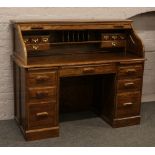 A carved oak modern roll top desk with fully fitted interior and two large file drawers.