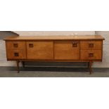 A retro teak sideboard with sliding doors to the centre section, raised over stepped supports.