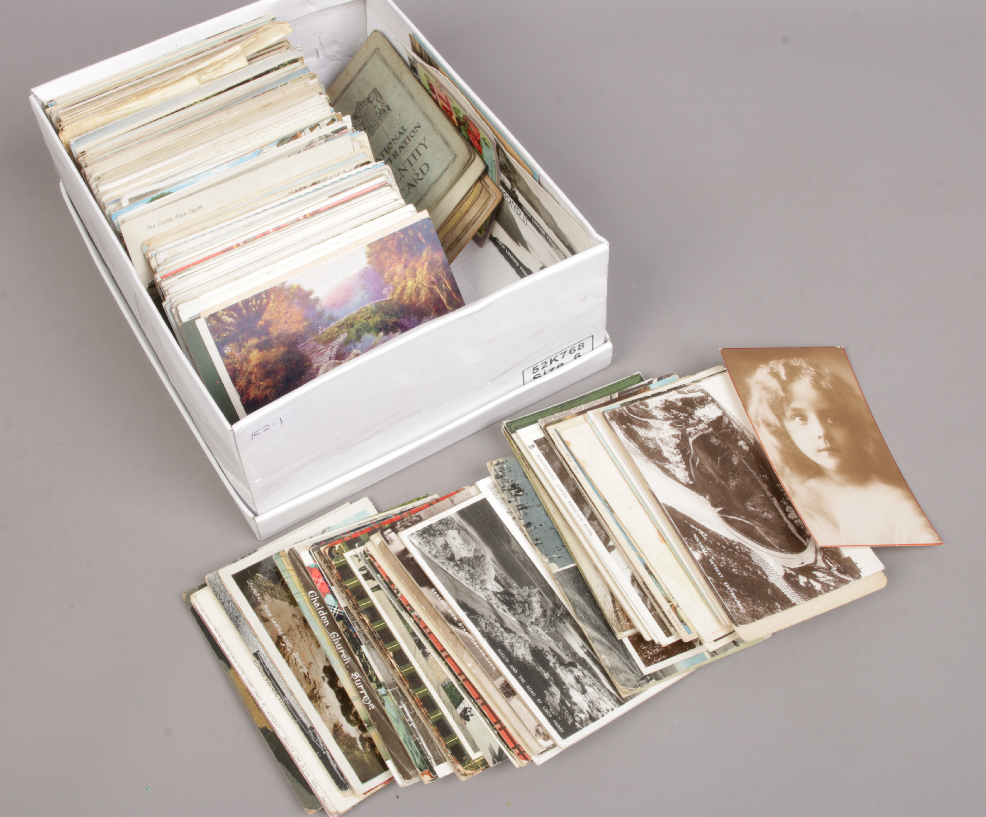 A shoe box of colour and monochrome postcards.