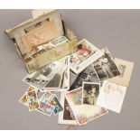 A tin of mixed ephemera to include photographs, greeting cards, Brooke Bond tea cards etc.