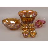 A carnival amber glass punch bowl and six cups along with a similar fruit bowl and a cranberry