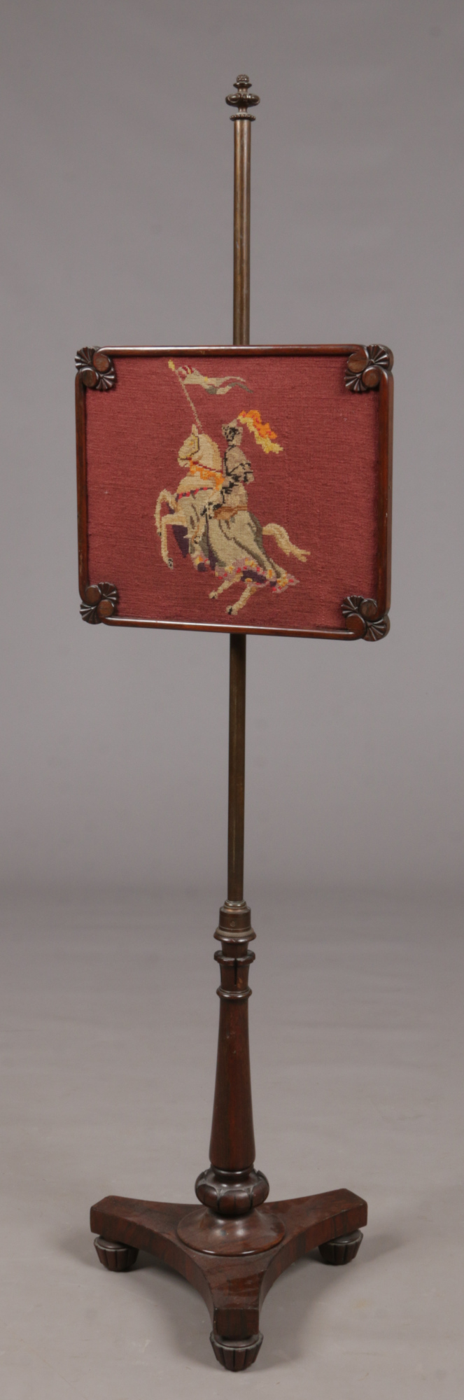 A Regency mahogany pole screen set with a woolwork panel of a knight on horseback.