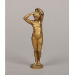 An Art Deco solid gilt bronze figure of a naked maiden stood and tending to her hair, raised on a