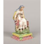 A Staffordshire pearlware figure, the Widow. Decorated in coloured glazed and raised on an ogee