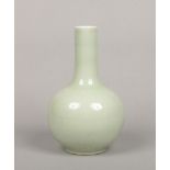 A Chinese celadon bottle vase. Carved in relief with stiff leaves to the collar and lotus scrolls to