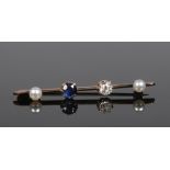 A yellow metal bar brooch set with a diamond and sapphire flanked by two pearls. Diamond