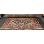 A Persian wool carpet, blue ground with a red border and having stylised flowers and urns, 310cm x