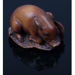 A fruitwood Netsuke formed as a recumbent pig with glass set eyes, signed.