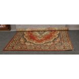 A maroon ground wool carpet square decorated with stylized flowers and a centre medallion.