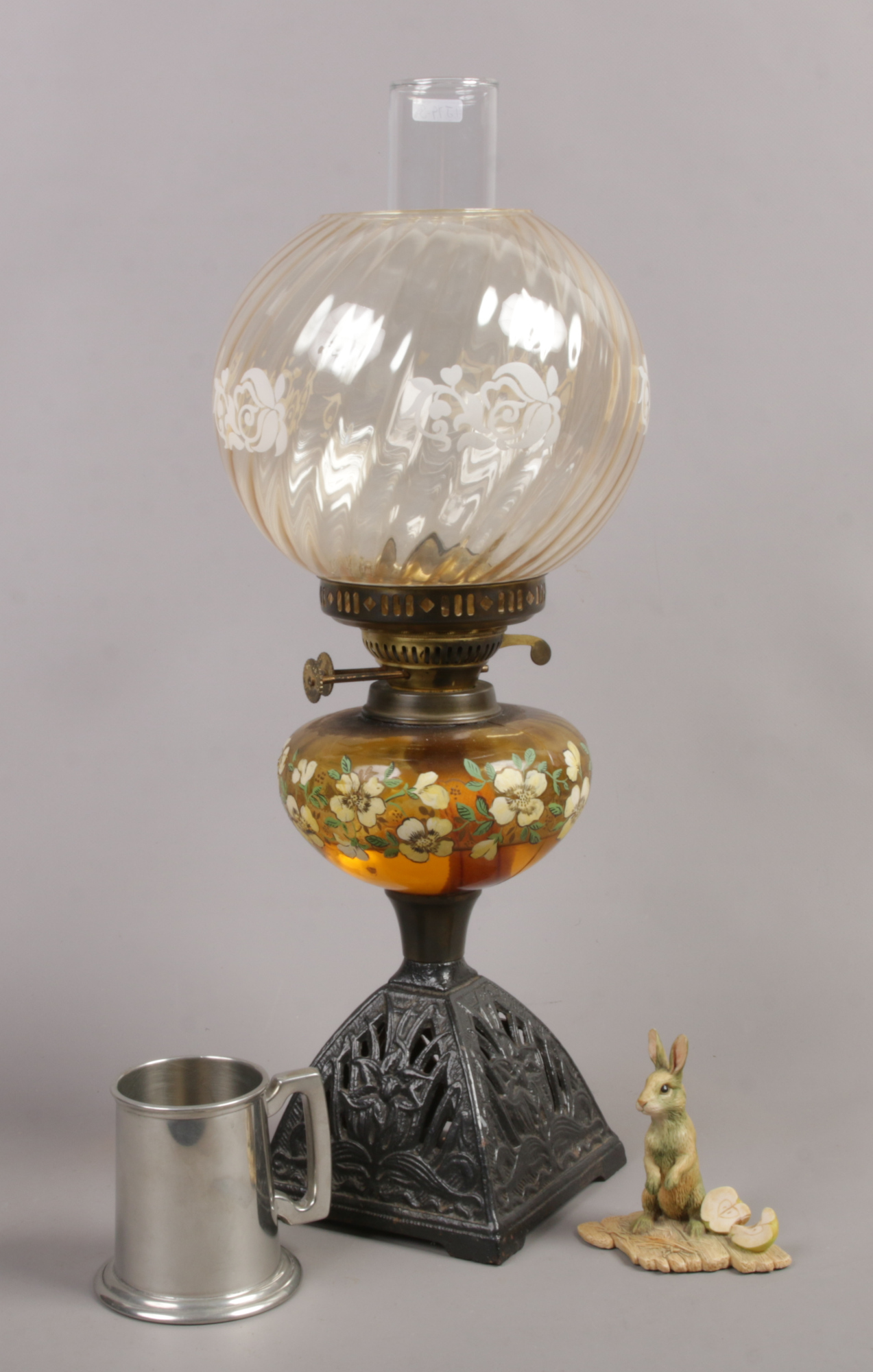 A Victorian cast iron base oil lamp with painted amber shade and swirl shade, along with Border