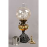 A Victorian cast iron base oil lamp with painted amber shade and swirl shade, along with Border