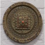 An Indian roundel wall plaque brass mounted with deities and coloured paste stones.