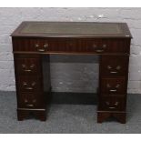 A hardwood twin pedestal desk of small proportions with green leather inset top.