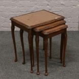 A nest of three carved mahogany occasional tables with inset brown leather tops raised on slender