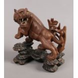 A 20th century oriental hardwood carving of a tiger with bone teeth and glass eyes.