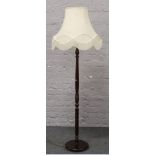 A turned mahogany standard lamp with cream shade.