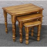 A nest of three hardwood bow front occasional tables raised on turned legs.