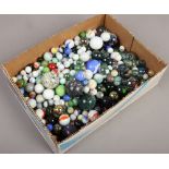 A box of polychrome glass marbles of various sizes some with transfer prints.