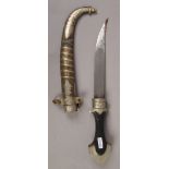 An eastern dagger with ebonised handle and brass and white metal scabbard.
