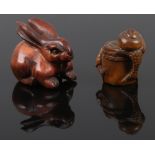 Two carved fruit wood netsuke one formed as slugs on a barrel the other as a hare with glass set