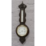 An early 20th century carved dark oak banjo barometer with porcelain dial.