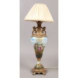 A continental porcelain and gilt metal table lamp decorated with putti and cream silk shade.