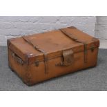 A large vintage leather mounted suitcase with metal studs and wooden runners.