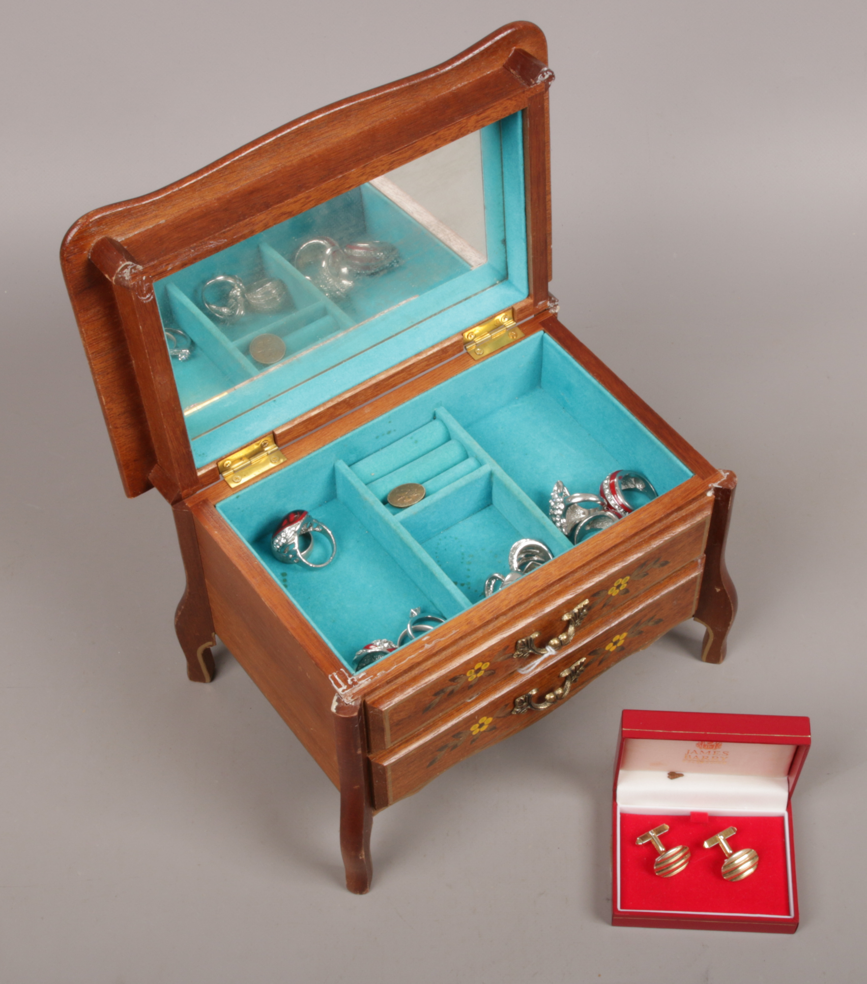 A musical jewellery box containing silver and white metal rings and a pair of yellow metal