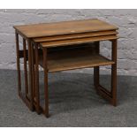 A carved nest of three teak occasional tables with lower rattan covered shelf.