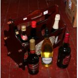 A magazine rack and contents of seven bottles of sealed alcohol to include Crofts sherry, Harvey