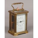 A brass carriage clock by William Widdop with visible escapement and key.