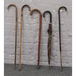 Four walking sticks, along with a ladies umbrella.