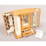 A wooden jewellery cabinet and contents of costume jewellery to include rings, necklaces, earrings