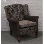 A 1930s wing arm chair raised on castered legs having been re-upholstered in two tone grey fabric.