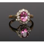 An 18ct gold halo cluster ring set with diamonds and a pink gemstone. Size O.