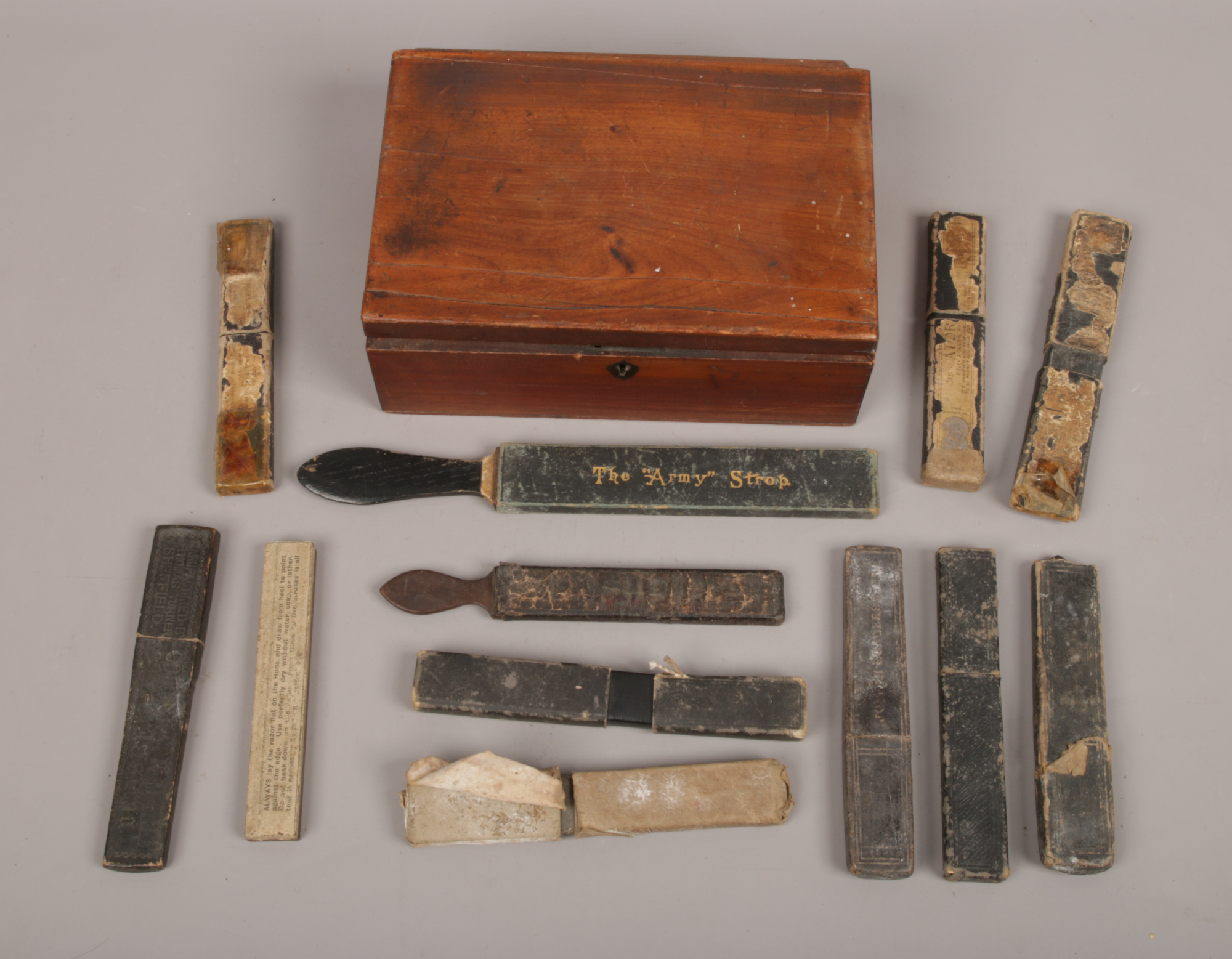 An antique mahogany box containing nine vintage boxed cut throat razors, two rolling strops and