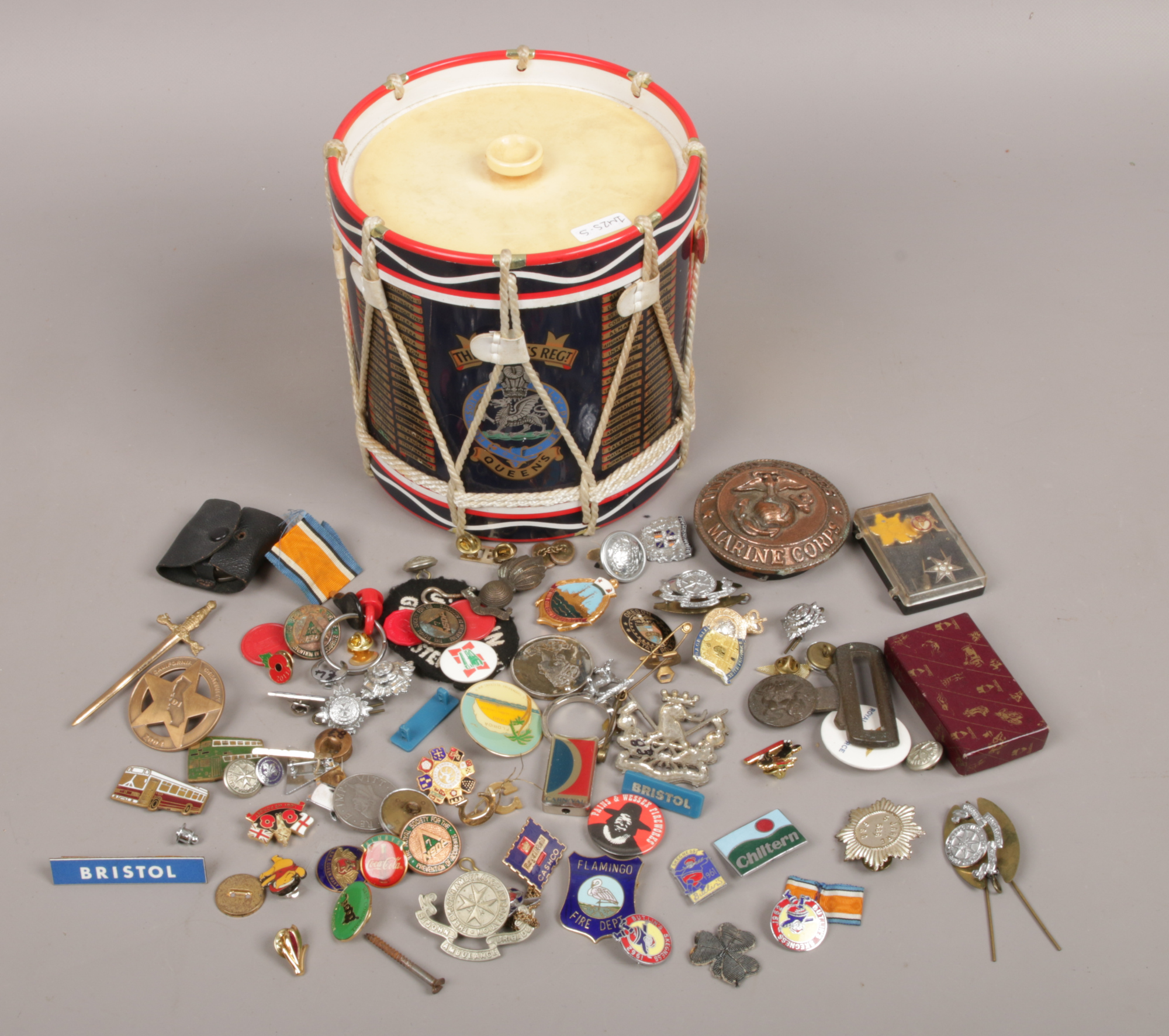 A Queens Regiment drum ice bucket with contents of collectables to include mostly badges.