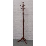 A turned coat stand raised on a tripod base.