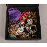 A leatherette box containing costume jewellery beads and brooches etc.