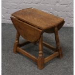 An oak drop leaf occasional table raised on splay turned supports.