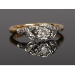 An Art Deco 18ct gold and platinum diamond solitaire ring with foliate shoulders. Size N.