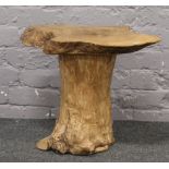 A rustic hardwood coffee table formed from a tree stump with walnut top.